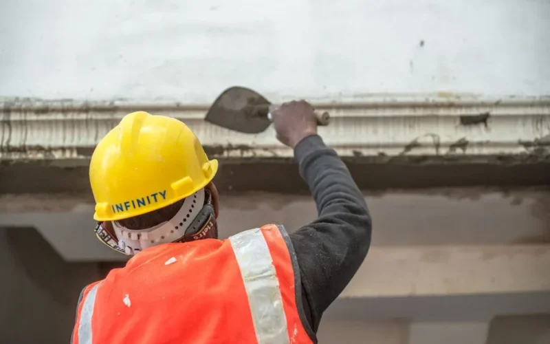 A construction worker in safety gear renovating an interior wall in Delhi, India.