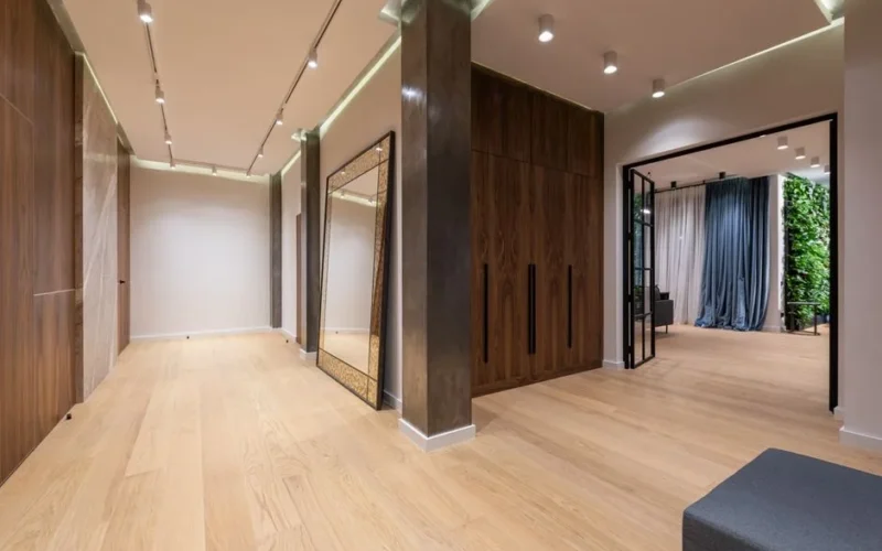 Interior of spacious hallway of modern apartment with wooden walls and floor and big doorway