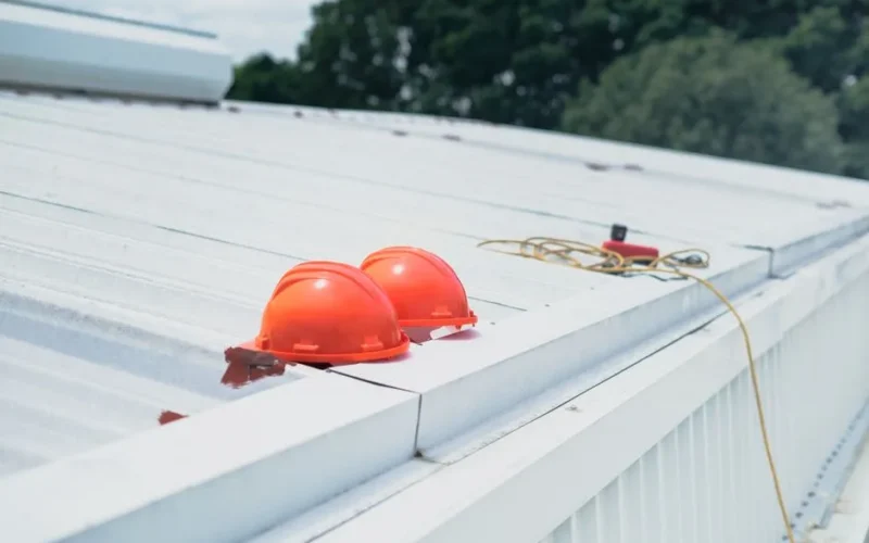 Red hard hats and safety equipment on a metal roof, emphasizing construction safety.