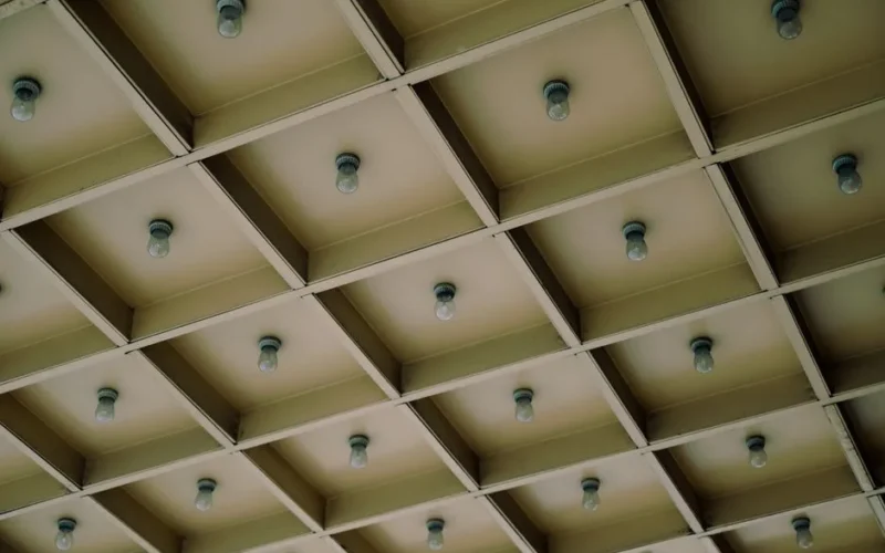 A modern geometric ceiling design featuring a grid pattern with light bulbs for architectural aesthetics.