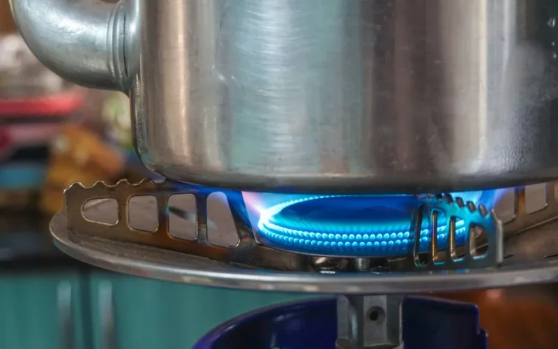A detailed image showing a gas stove burner with a pot above, highlighting kitchen heat and flame.