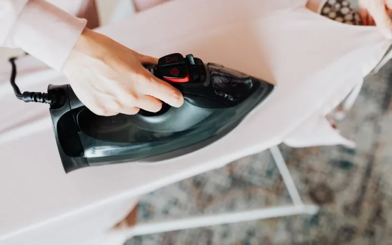 Overhead view of a person ironing clothes on a board at home, showcasing a domestic chore.