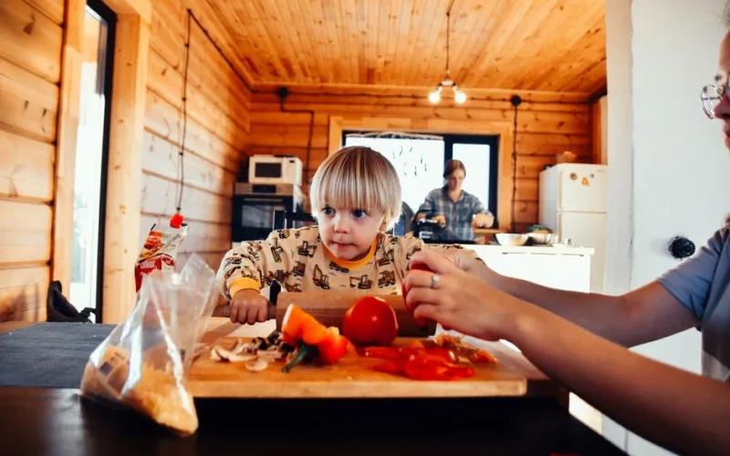 A young child assists in food preparation at home, fostering early culinary skills.