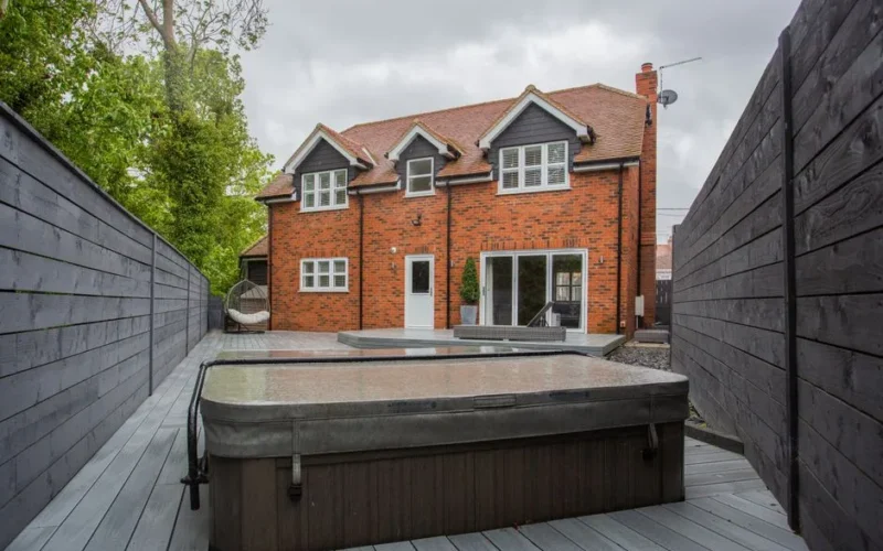 A picturesque backyard view of a modern brick house with a jacuzzi.