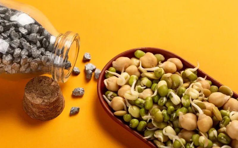 Healthy sprouted chickpeas and beans with iron nuggets on a vibrant yellow backdrop.