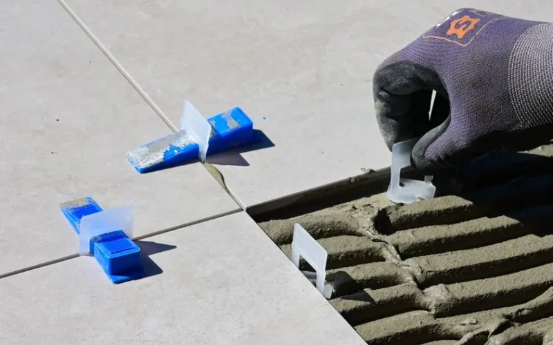 Close-up of professional tile installation using spacers and levelers for perfect alignment.