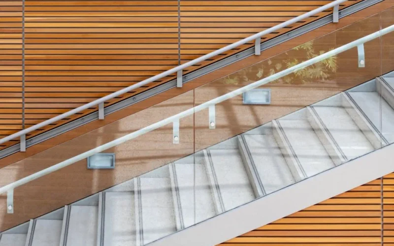 A contemporary staircase featuring glass railings and wooden paneling, highlighting modern architecture.