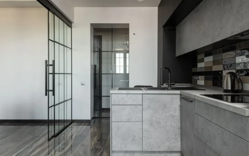 Contemporary kitchen featuring grey cabinets, glass partition, and marble elements.