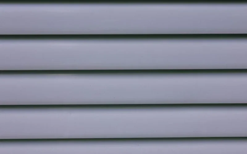 Detailed close-up of gray layered wall paneling showing lines and shadows.
