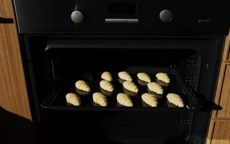 Close-up of fresh croissants baking in the oven, showcasing their golden, flaky texture.