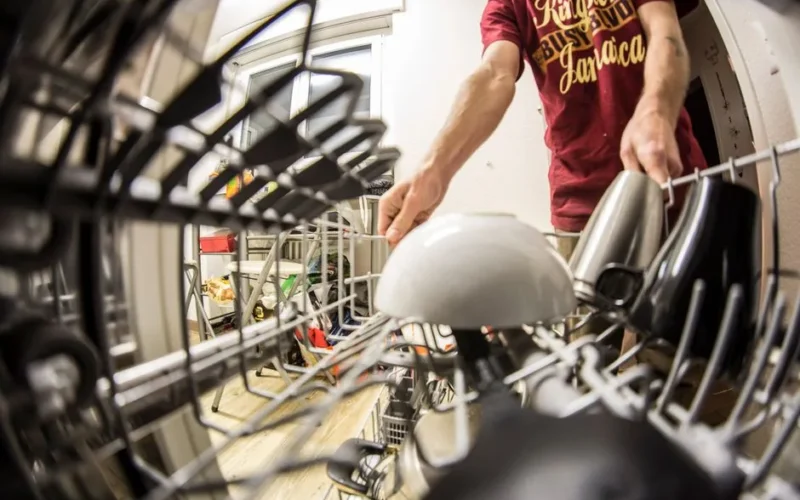 POV perspective of an adult loading dishes into a dishwasher in a home kitchen.