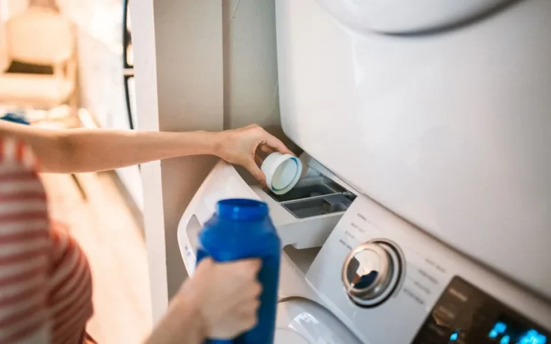 Close-up of a person pouring detergent into a front-loading washer, emphasizing household chores.