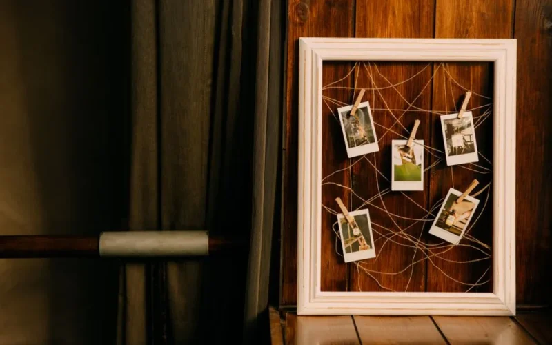 A rustic wooden frame holds Polaroid photos, perfect for vintage decor lovers.