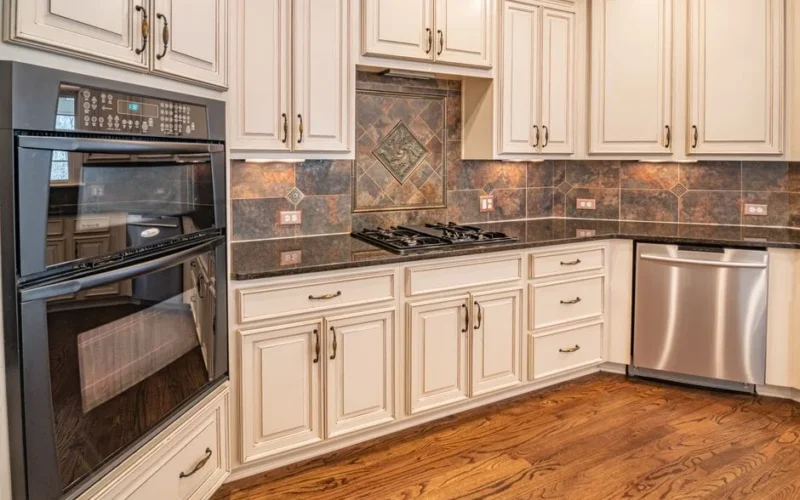 A modern kitchen featuring cabinets, a dishwasher, and a double oven with hardwood floors.