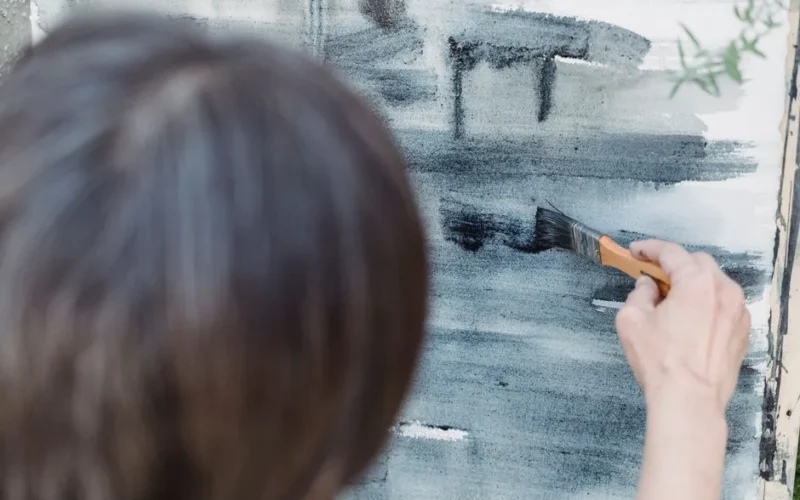 Close-up of a person painting abstract brushstrokes on canvas, showcasing artistic creativity.
