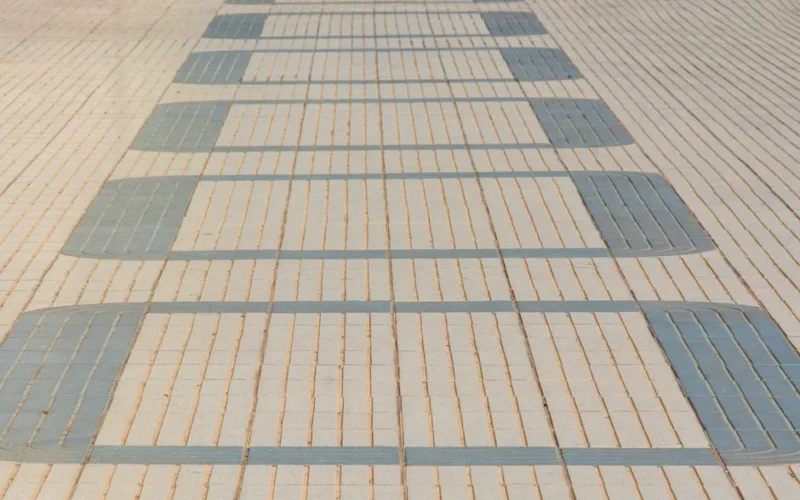 Geometric design on tiled pavement, featuring light and dark rectangular shapes.
