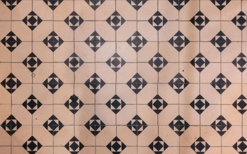 Vintage geometric floor tile pattern with black diamond shapes on beige background.