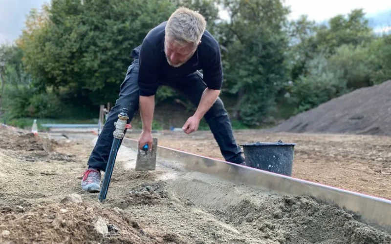A construction worker leveling ground at a work site in Höchstenbach, Germany.