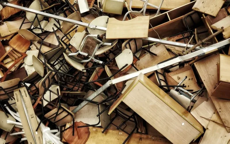 A chaotic pile of discarded wooden furniture and chairs seen from above.
