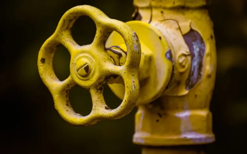 Close-up view of a rusty yellow shut-off valve, emphasizing industrial wear.